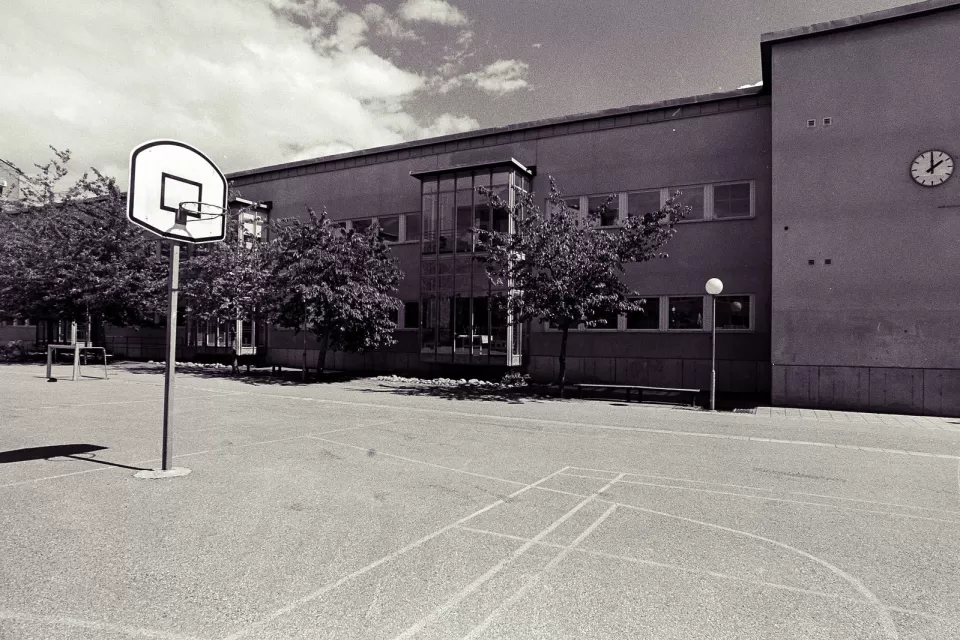 Low-saturation image of a concrete schoolyard with basketball hoop